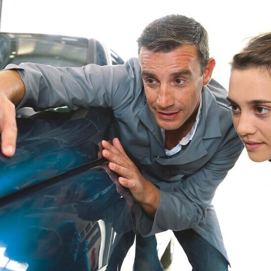 Portrait d'un alternant accompagné de son tuteur examinent ensemble le moteur d'une voiture